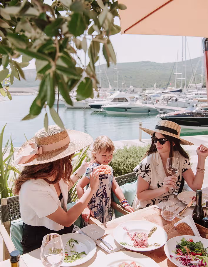 Guests dining on a waterfront terrace overlooking the marina